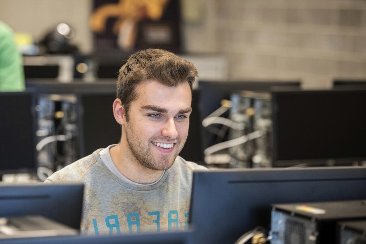 A person working at a computer in a bright shared workspace.