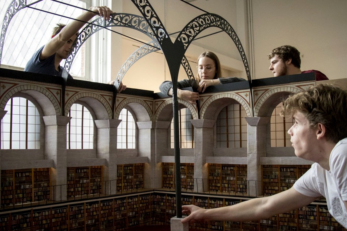 People looking across the ornate interior of a large historic hall.