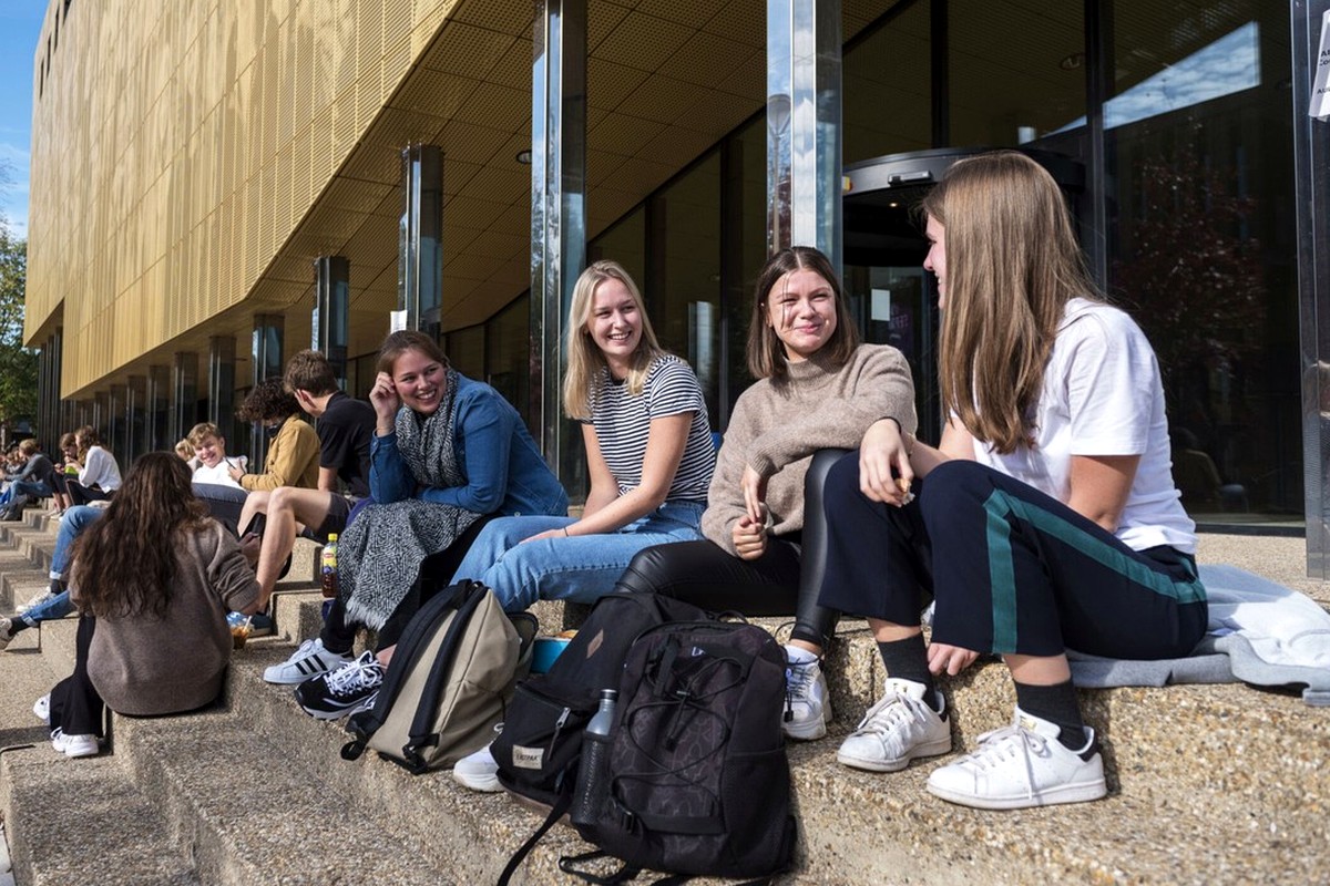 A group of students talking together outside a modern building in daylight.
